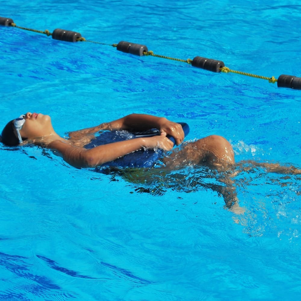 Child floating on back holding a kickboard