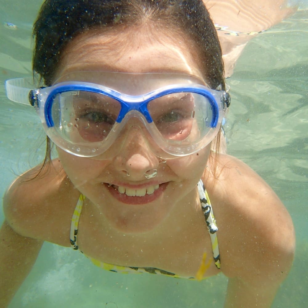 Smiling swimmer wearing blue goggles underwater