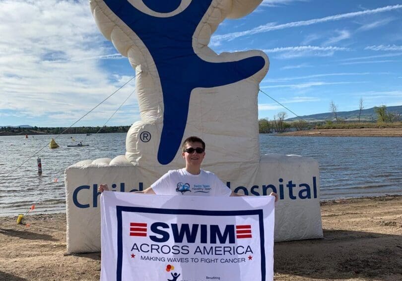 A man holding up a sign in front of a lake.