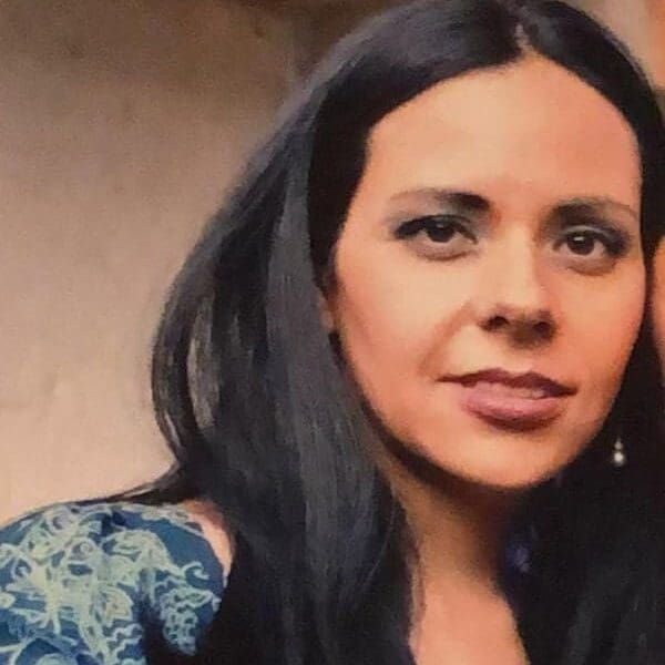 A woman with long black hair wearing blue and white.